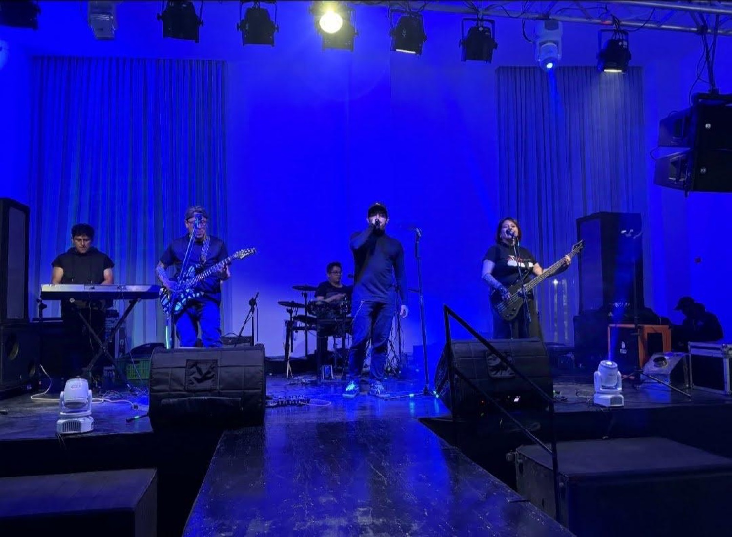 La banda en un escenario grande con luces azules